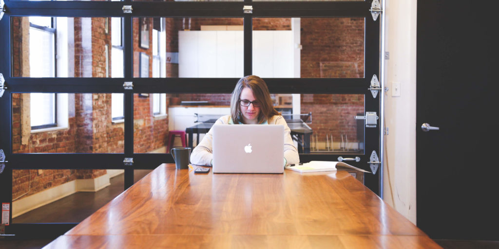 A female working on a laptop at a wooden table