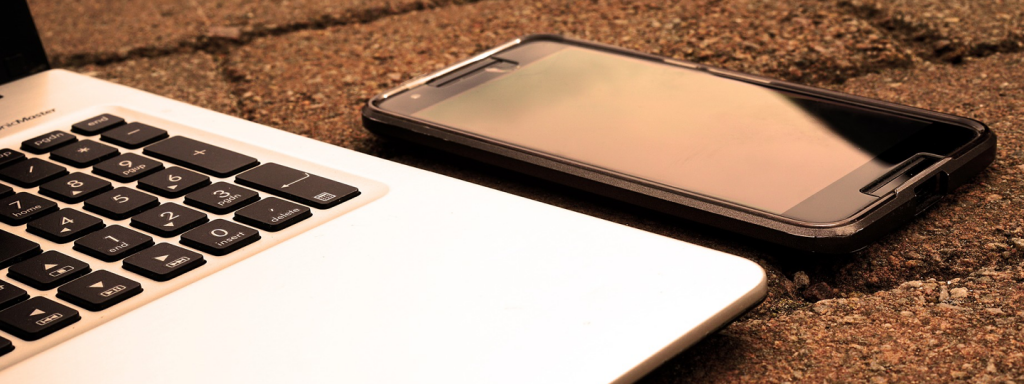 An iPhone sitting next to a laptop